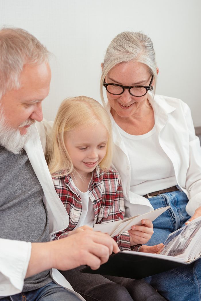 Services Elderly couple and young girl enjoying family photo album at home.